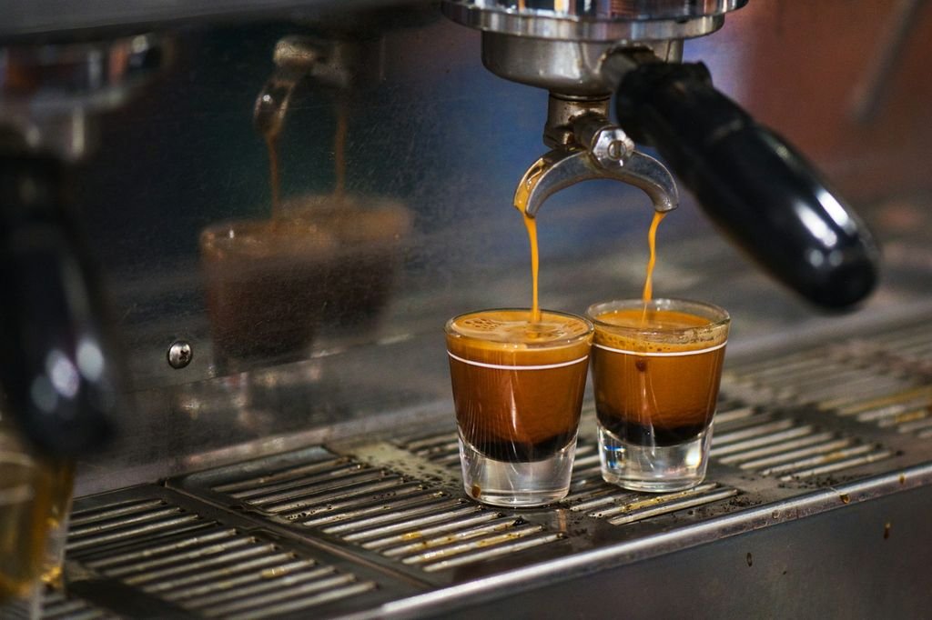 Espresso makinesinden iki küçük bardağa akan espresso