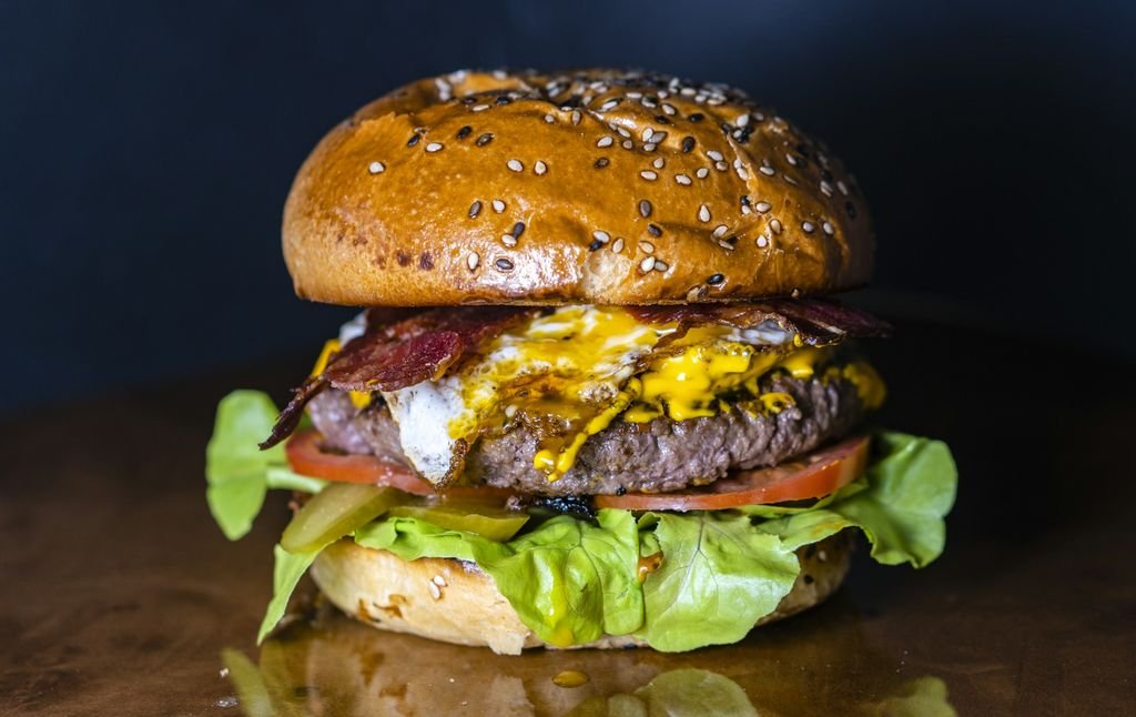 Koyu zemin üzerinde eritilmiş peynirli ve marullu bir burger