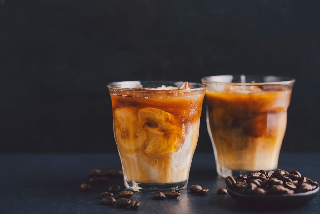 Koyu zemin üzerinde buzlu iki bardak soğuk latte