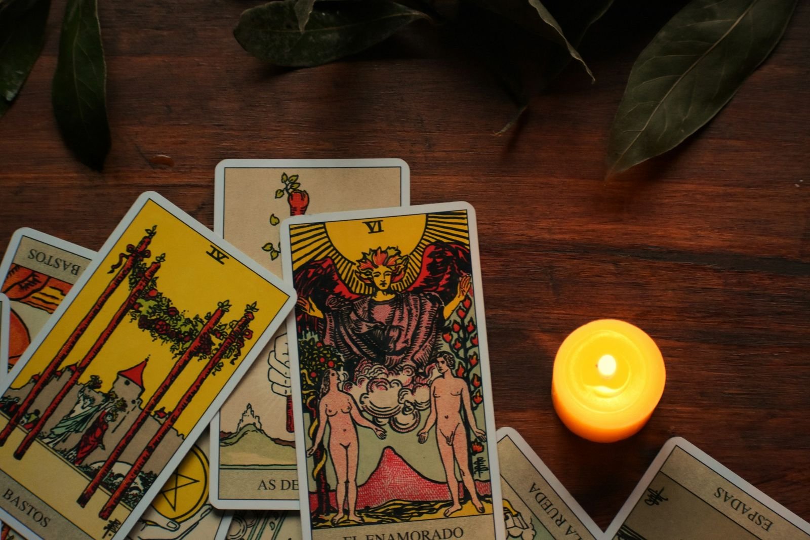 Ahşap masa üzerinde tarot kartları ve yanan bir mum