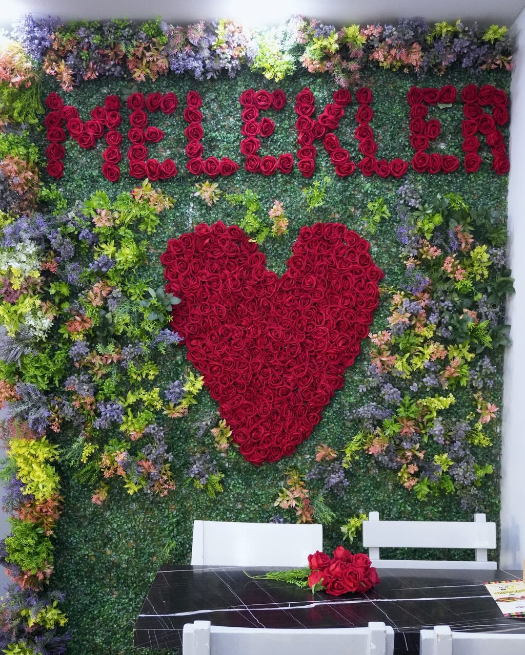 Kırmızı güllerle yazılmış MELEKLER yazısı ve kalp şekli olan rengârenk çiçek duvarı